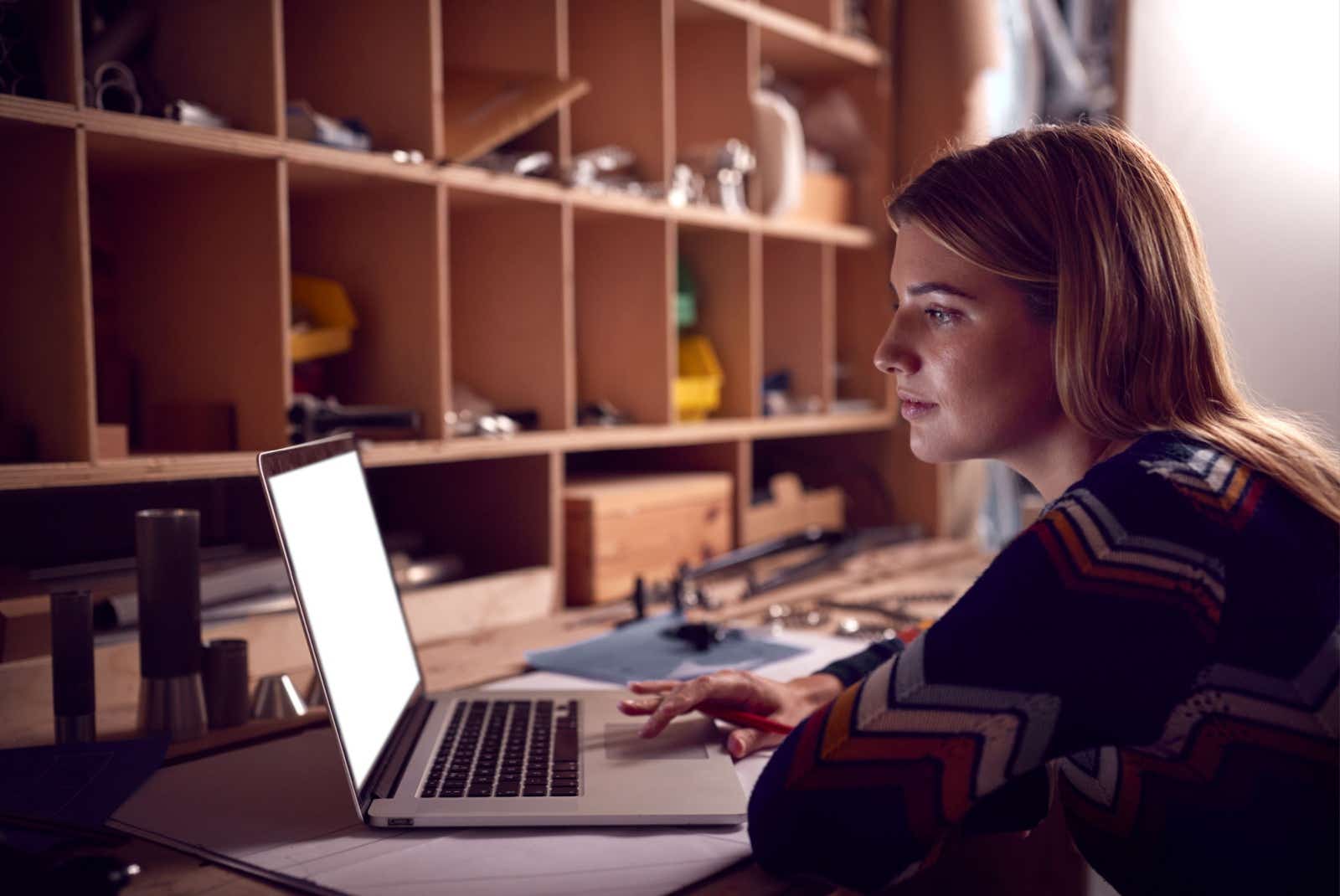 Businesswoman working on a laptop in a workshop at night.